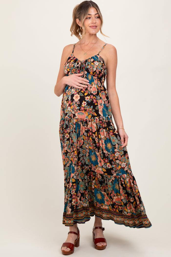 woman wearing a black floral maternity maxi dress and cradling her baby bump