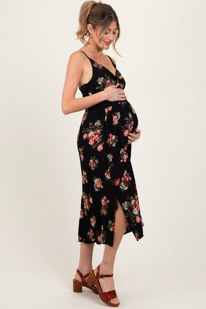 woman wearing a black floral maternity dress with a side slit, holding her baby bump