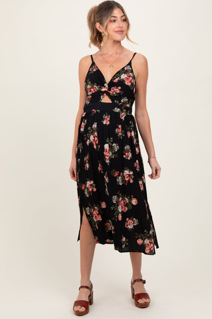 woman wearing a black floral maternity dress with a cutout detail and a flowy skirt, showcasing her baby bump