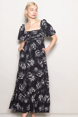 woman wearing a black floral print maxi dress with puff sleeves and side pockets