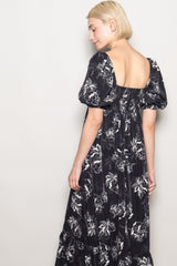 woman wearing a black floral puff sleeve maxi dress with a square neckline and gathered back detail