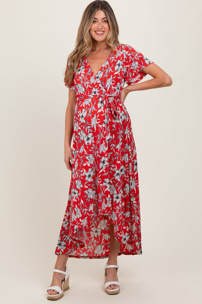 woman wearing a red floral print maternity maxi dress with short sleeves and a tie waist, showing her baby bump