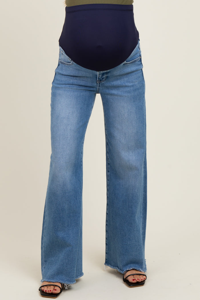 woman wearing a pair of light blue maternity flared jeans with a navy waistband and sandals