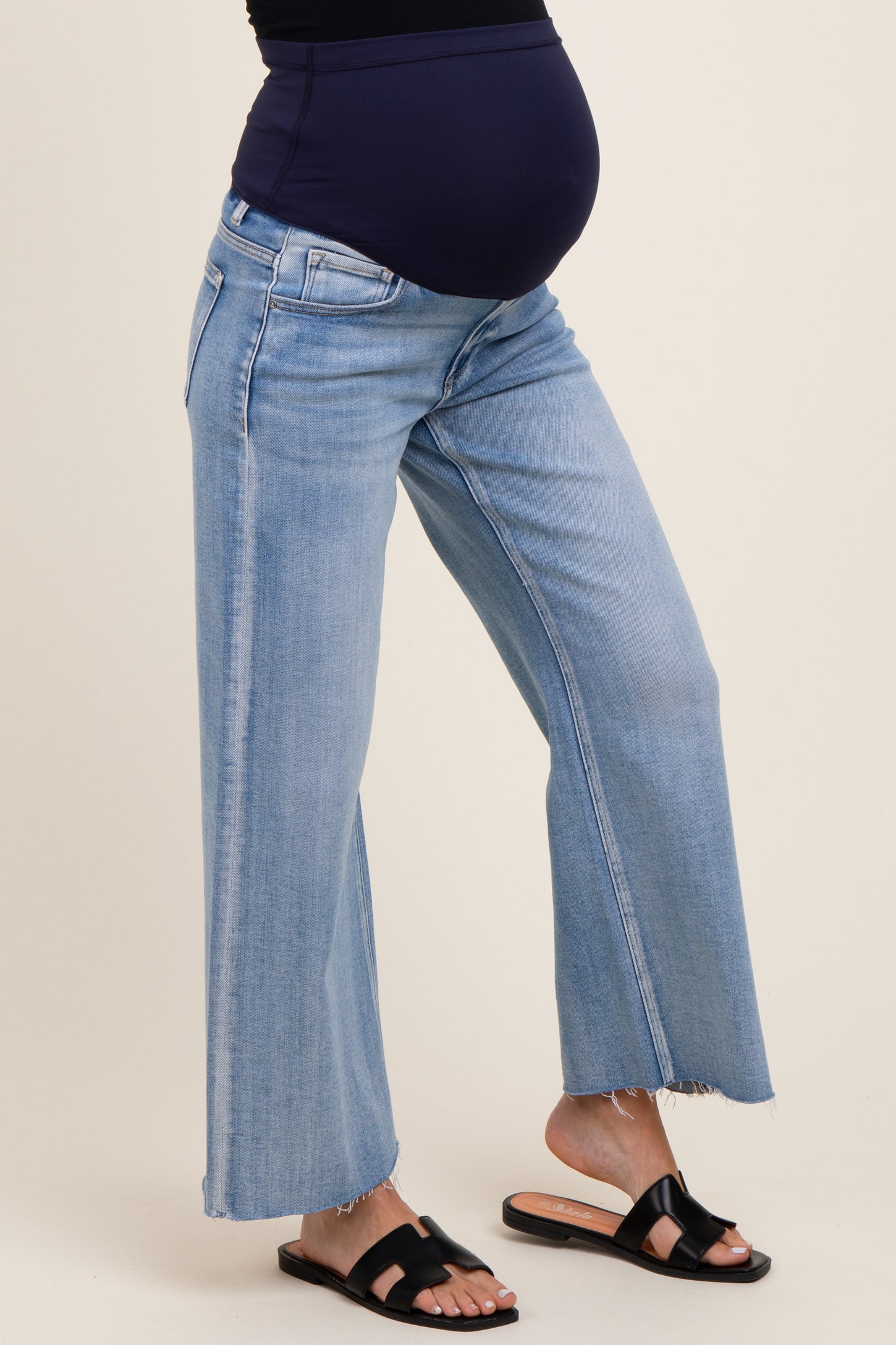 woman wearing light blue maternity wide-leg jeans with a frayed hem and a visible baby bump