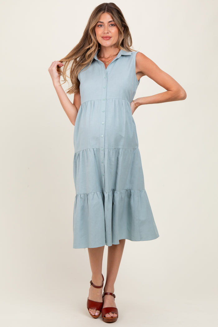 woman wearing a light blue sleeveless maternity dress with a button-down front and tiered skirt, showcasing her baby bump