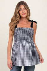 woman wearing a black and white gingham maternity top with adjustable straps and a smocked bodice
