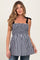 woman wearing a black and white gingham maternity top with adjustable straps and a smocked bodice