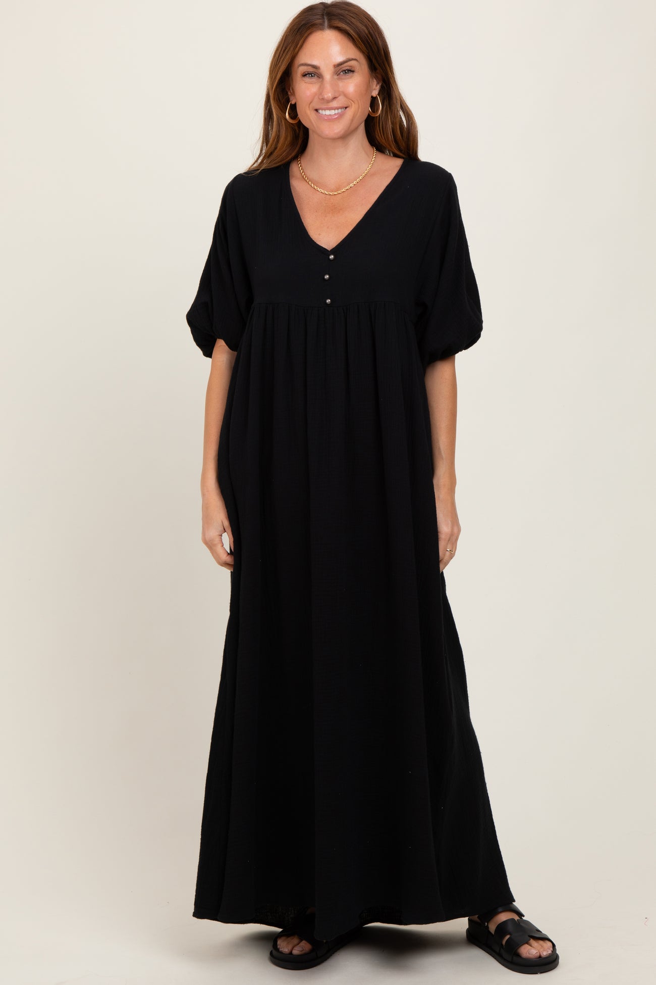 woman wearing a black maxi dress with a v-neckline, puff sleeves, and button details