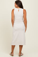 woman wearing a light beige maternity midi dress with a keyhole back detail and subtle pattern