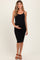 woman wearing a black ribbed maternity dress with spaghetti straps and holding her baby bump