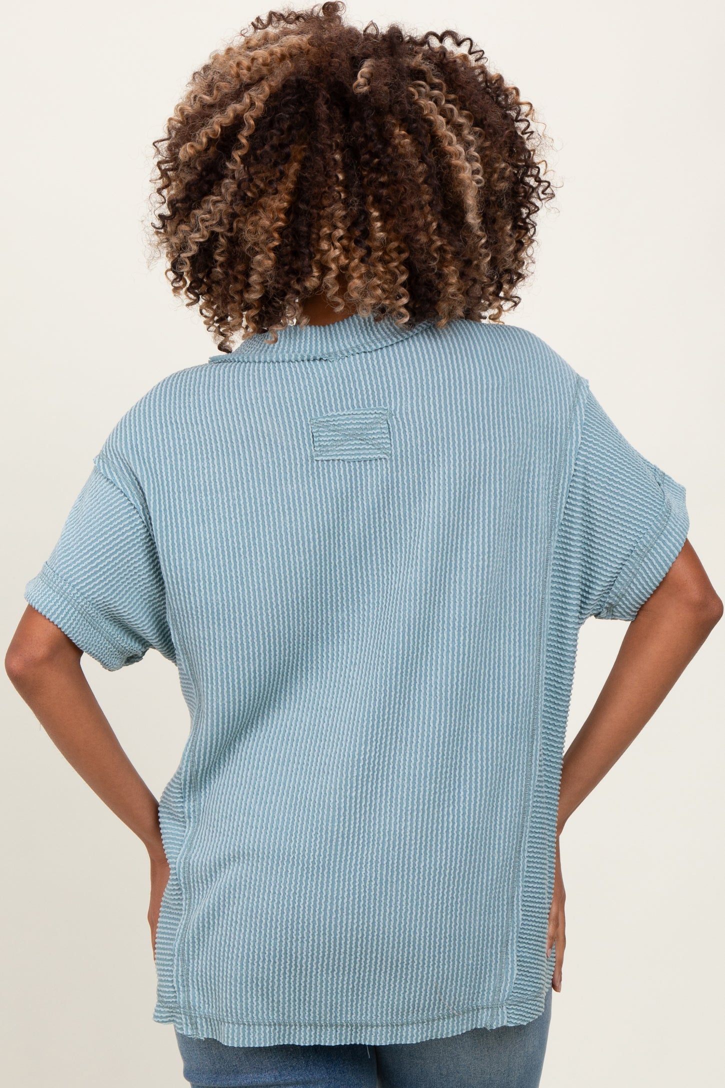 woman wearing a light blue short sleeve ribbed maternity top, showing the back view, with a relaxed fit