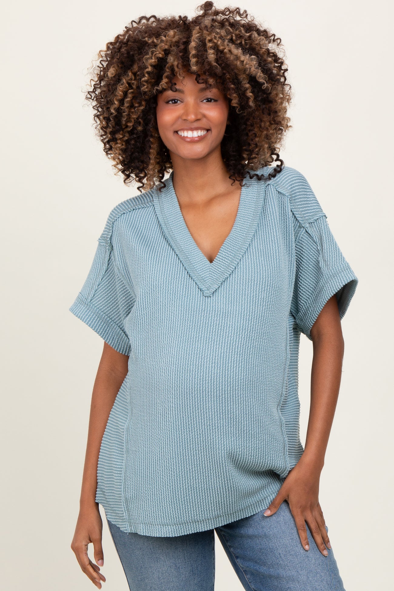 woman wearing a light blue short sleeve maternity top with a v-neck and a baby bump visible
