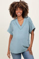 woman wearing a light blue short sleeve maternity top with a v-neck and a baby bump visible