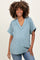 woman wearing a light blue short sleeve maternity top with a v-neck and a baby bump visible