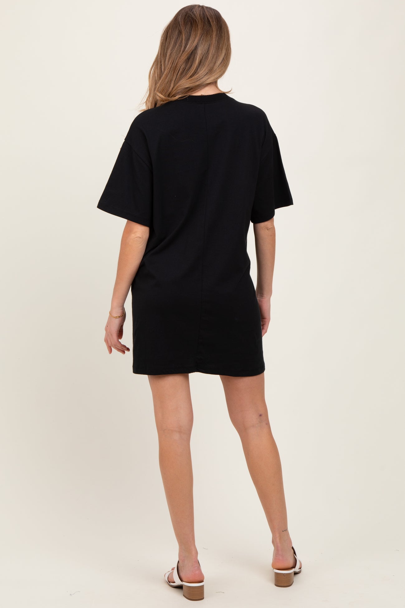 woman wearing a black short sleeve maternity dress, standing with her back to the camera