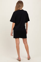 woman wearing a black short sleeve maternity dress, standing with her back to the camera