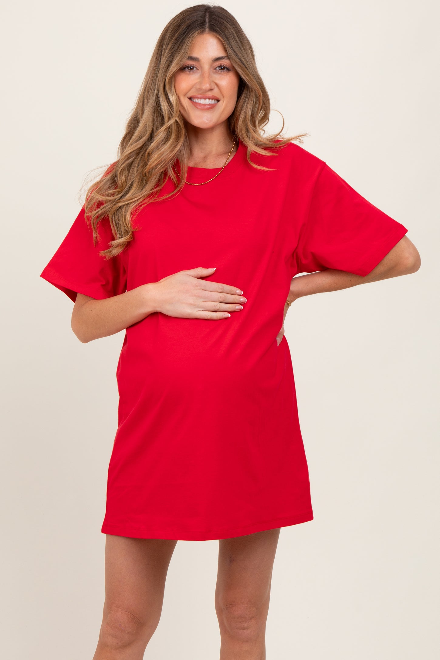woman wearing a bright red short sleeve maternity dress and holding her baby bump