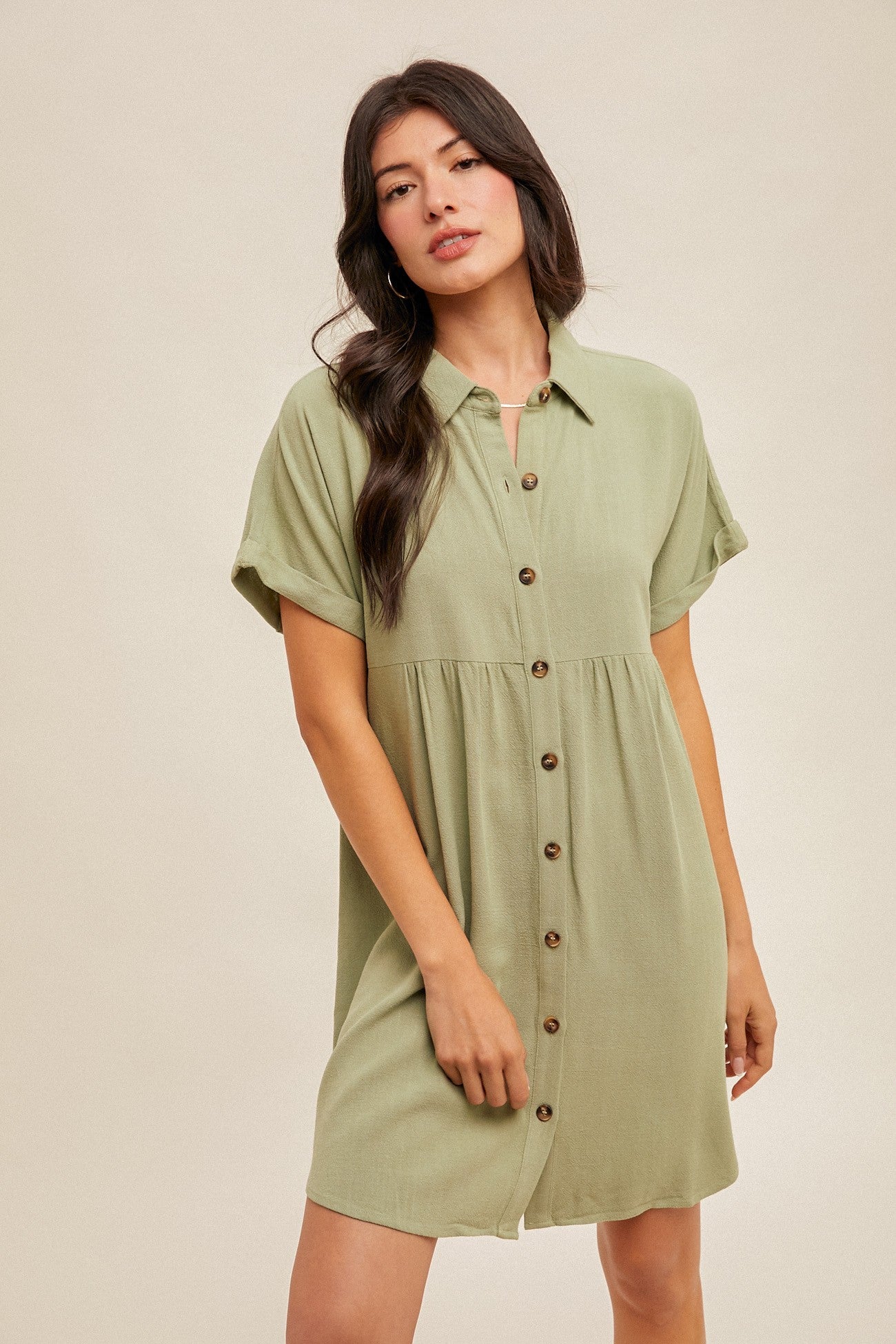 woman wearing a short sleeve light green button-up dress with a relaxed fit and tiered skirt