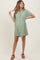 woman wearing a sage green short sleeve maternity dress with buttons and a gathered waist, showing her baby bump