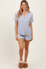 woman wearing a light gray short-sleeve pajama set with buttons and matching shorts, paired with cozy slippers