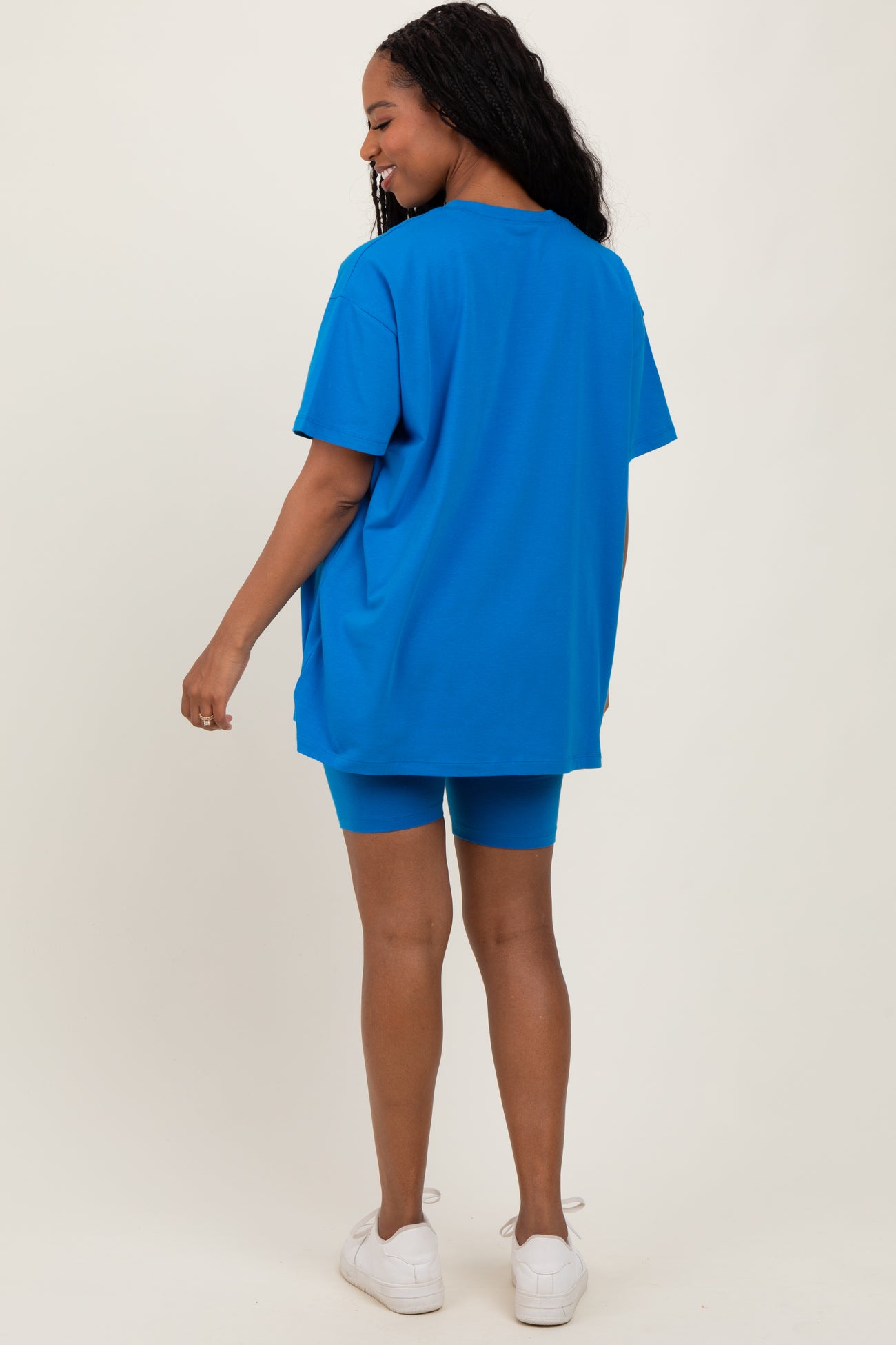 woman wearing a bright blue oversized t-shirt and matching bike shorts, with her back turned to the camera