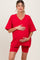 woman wearing a red oversized maternity t-shirt and red maternity bike shorts, holding her baby bump