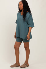 woman wearing a teal oversized v-neck t-shirt and matching bike shorts, paired with brown slip-on shoes
