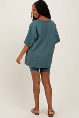 woman wearing an oversized teal t-shirt and matching biker shorts, facing away from the camera