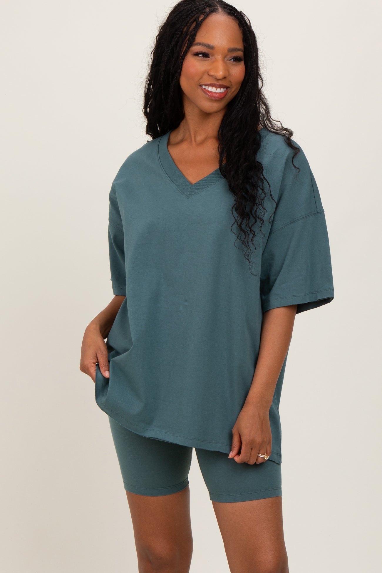 woman wearing a teal oversized v-neck t-shirt and matching bike shorts in a relaxed pose