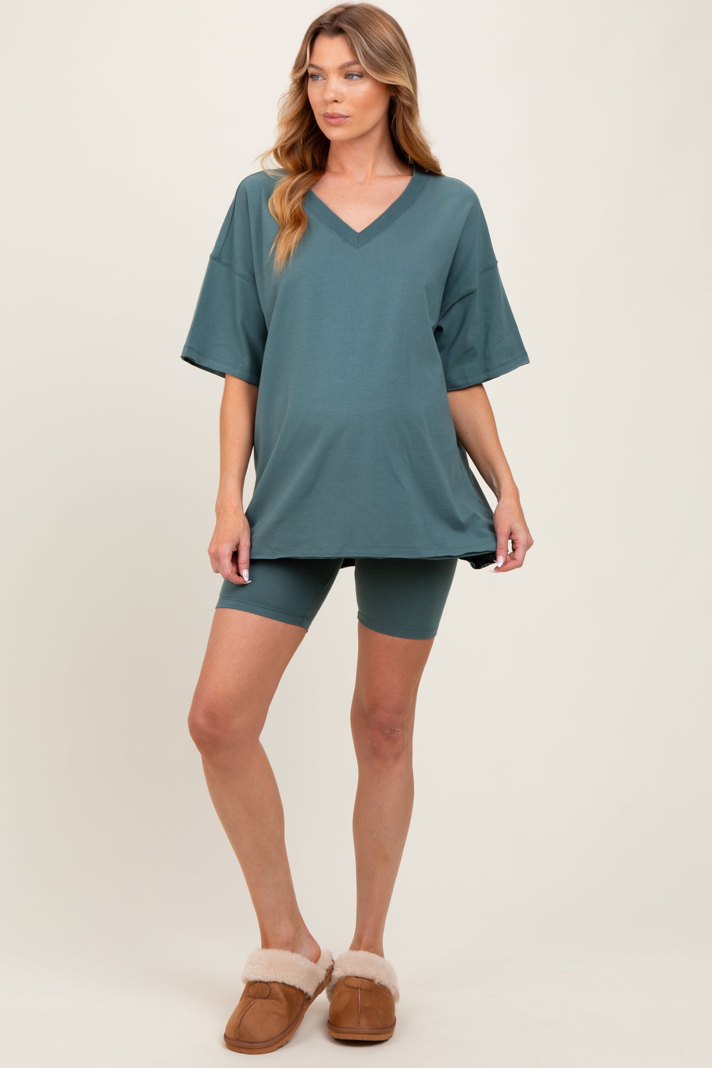 woman wearing a teal maternity oversized t-shirt and matching bike shorts, with a visible baby bump