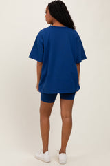 woman wearing a dark blue oversized t-shirt and matching bike shorts, standing with her back to the camera