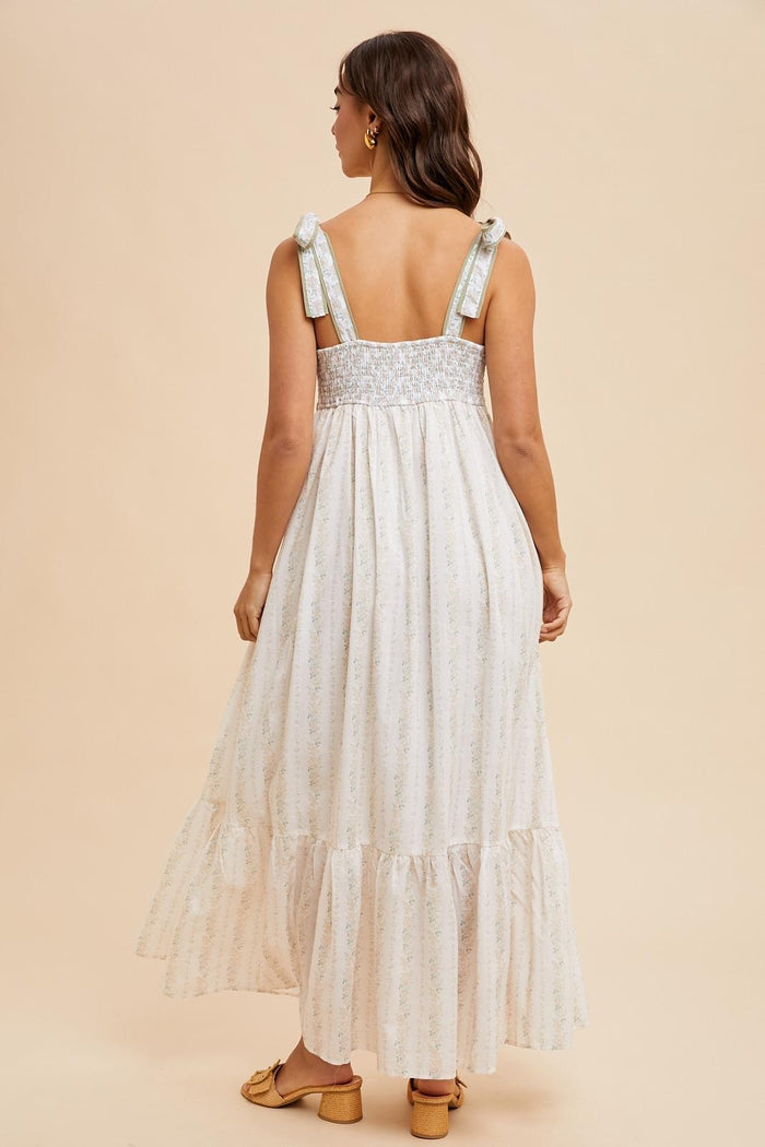 woman wearing a back view of a light floral maxi dress with tie straps and a smocked bodice
