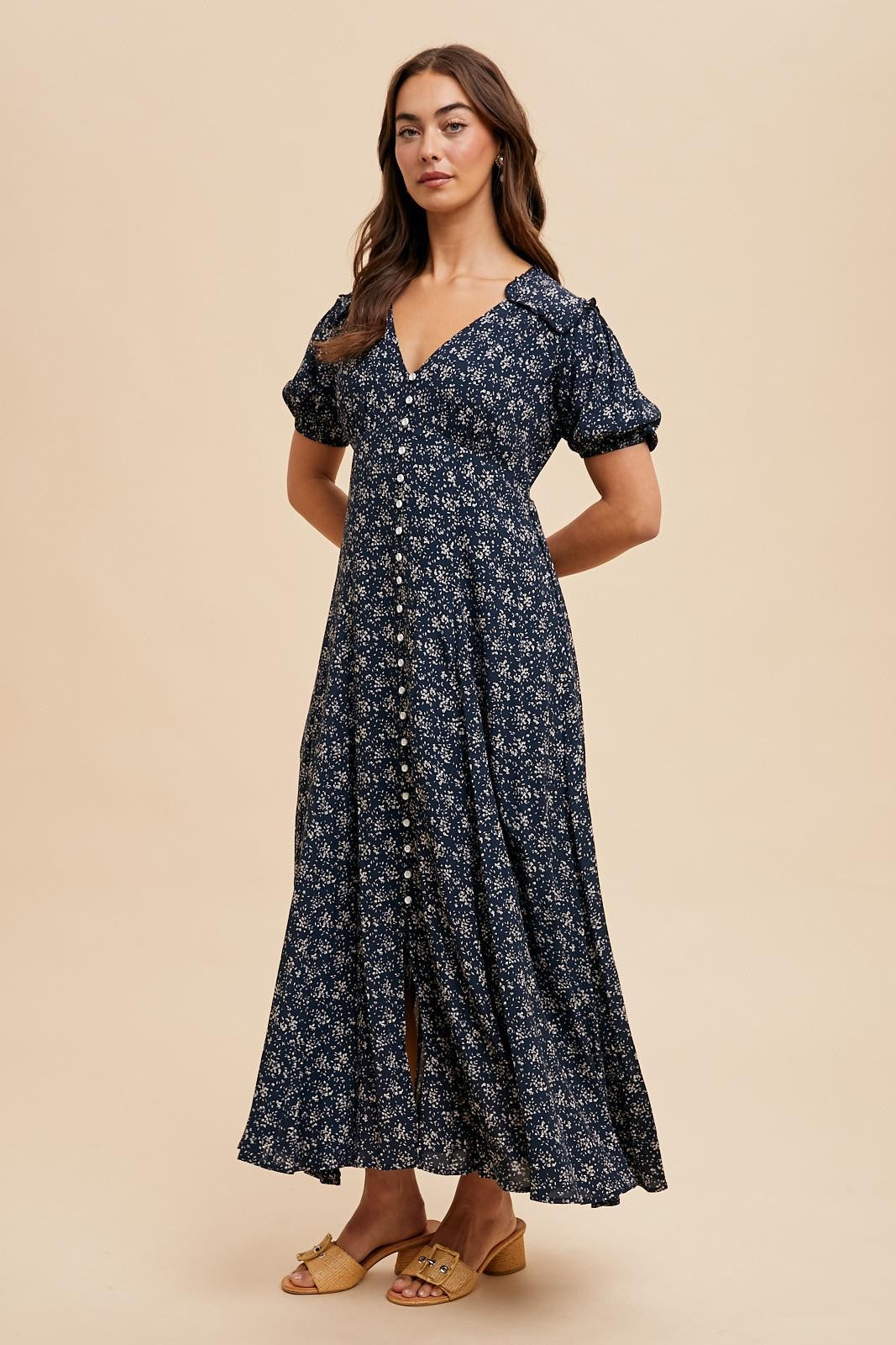 woman wearing a navy blue floral maxi dress with puff sleeves and button closure