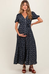 woman wearing a navy floral maternity maxi dress and holding her baby bump