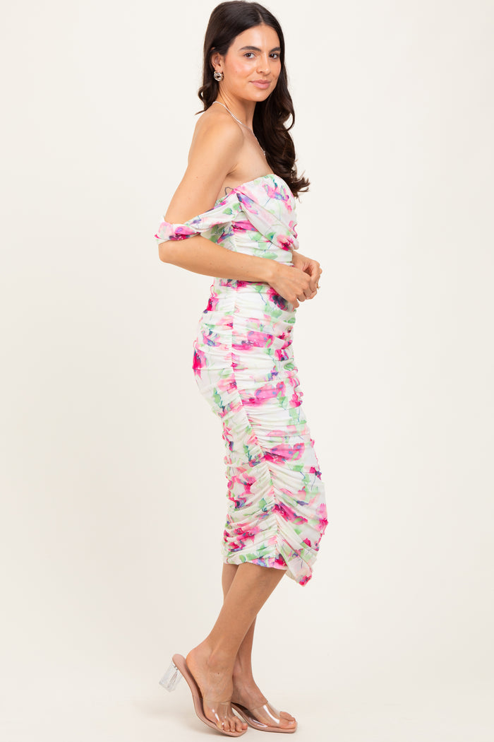 woman wearing a colorful off-the-shoulder fitted dress with ruched details and a midi length