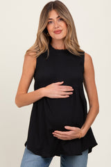 woman wearing a black sleeveless maternity top and gently cradling her baby bump