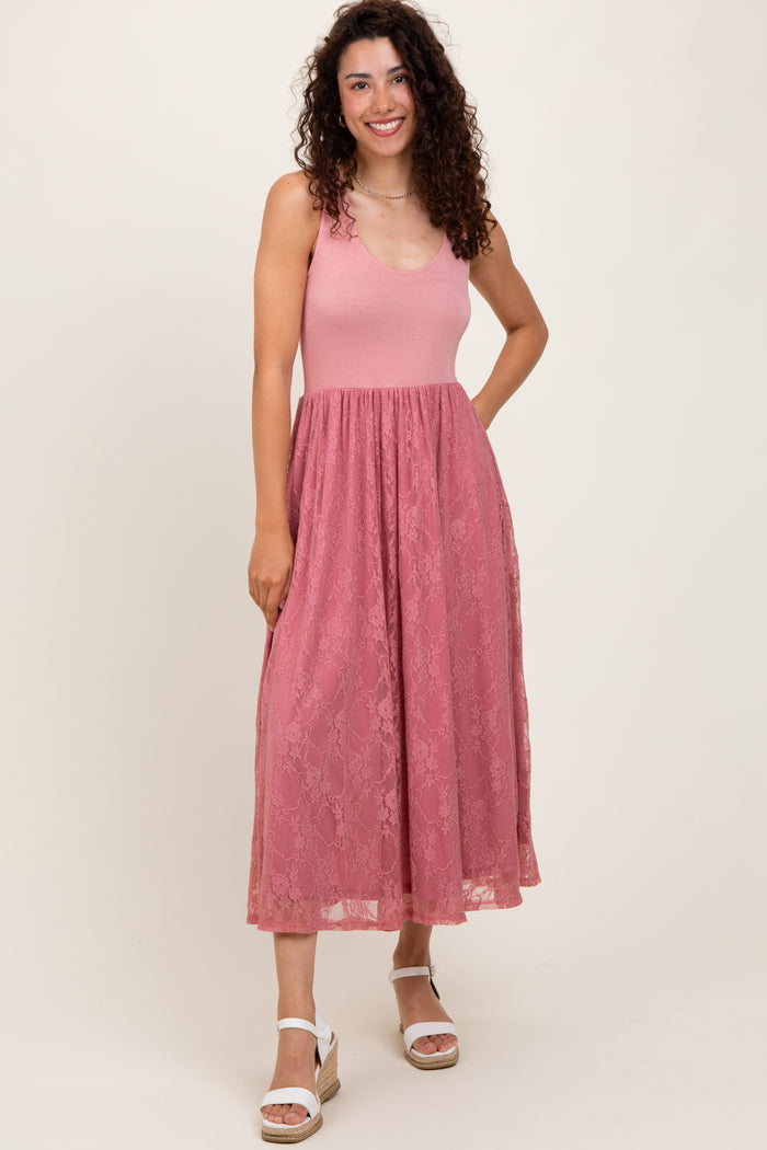 woman wearing a pink lace maxi dress with a fitted bodice and flared skirt, standing and smiling