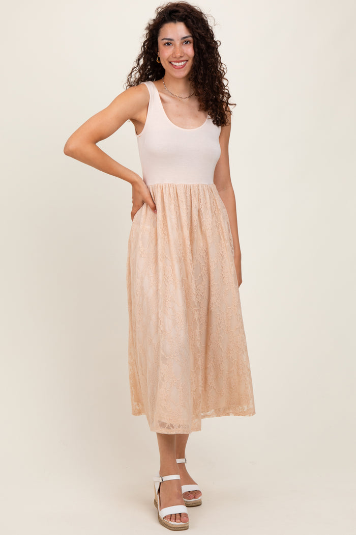 woman wearing a beige sleeveless dress with a fitted top and lace skirt, smiling against a neutral background