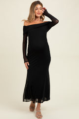woman wearing a black off-the-shoulder maternity dress with long sheer sleeves and a visible baby bump