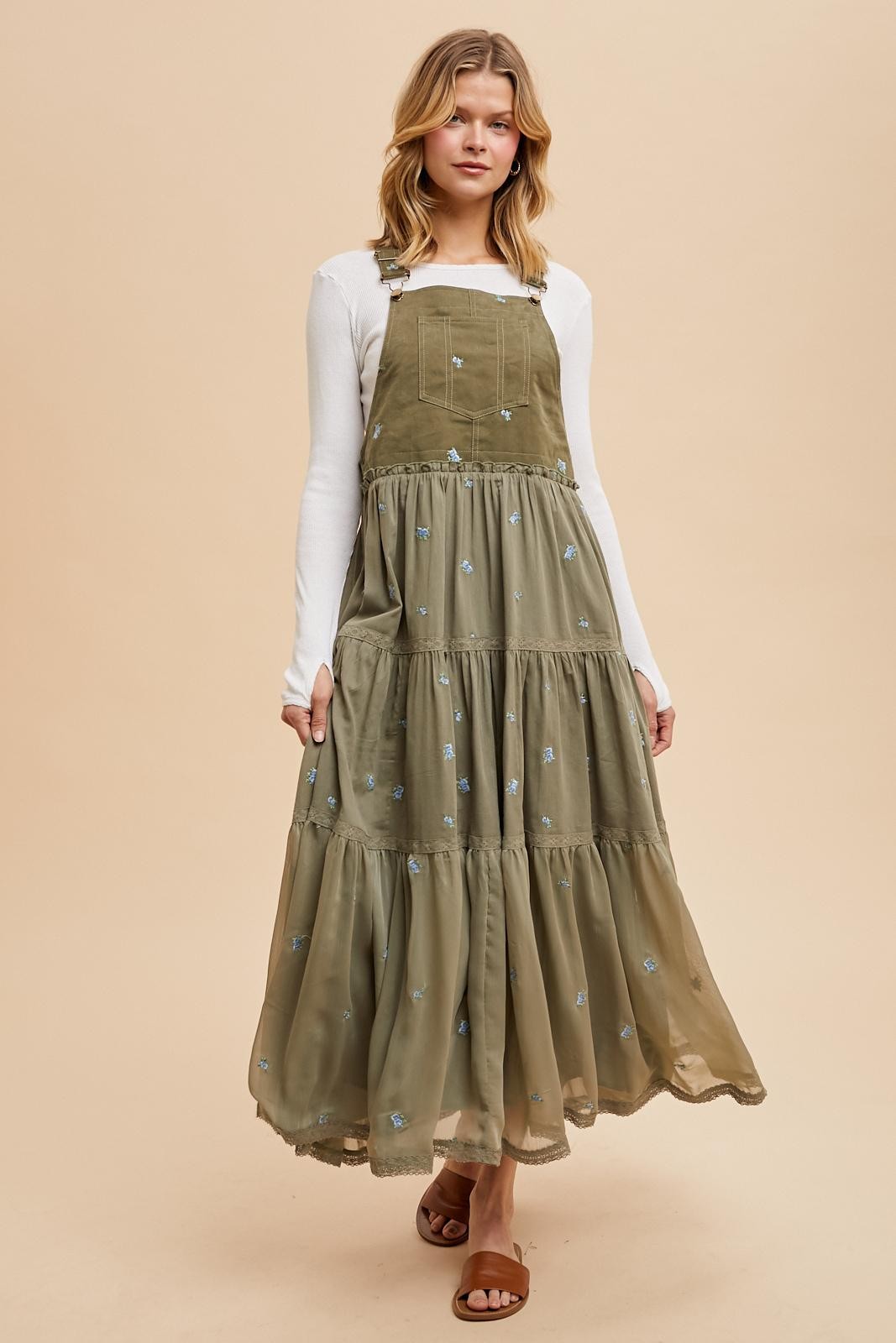 woman wearing a long olive green tiered maxi dress with embroidered flowers and adjustable straps