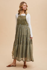 woman wearing an olive green embroidered maxi dress with a tiered design and adjustable straps