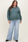 woman wearing a teal oversized sweater and light blue wide-leg jeans, showcasing her baby bump