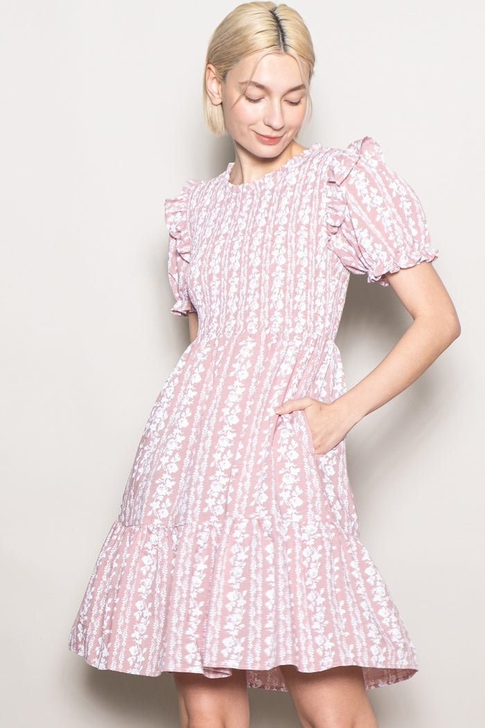 woman wearing a pink floral print puff sleeve dress with a tiered skirt and pockets