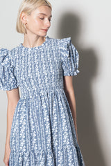 woman wearing a light blue floral puff sleeve dress with smocked bodice and tiered skirt