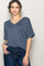woman wearing a navy blue v-neck short sleeve top with a front pocket and rolled sleeves paired with high-waisted jeans