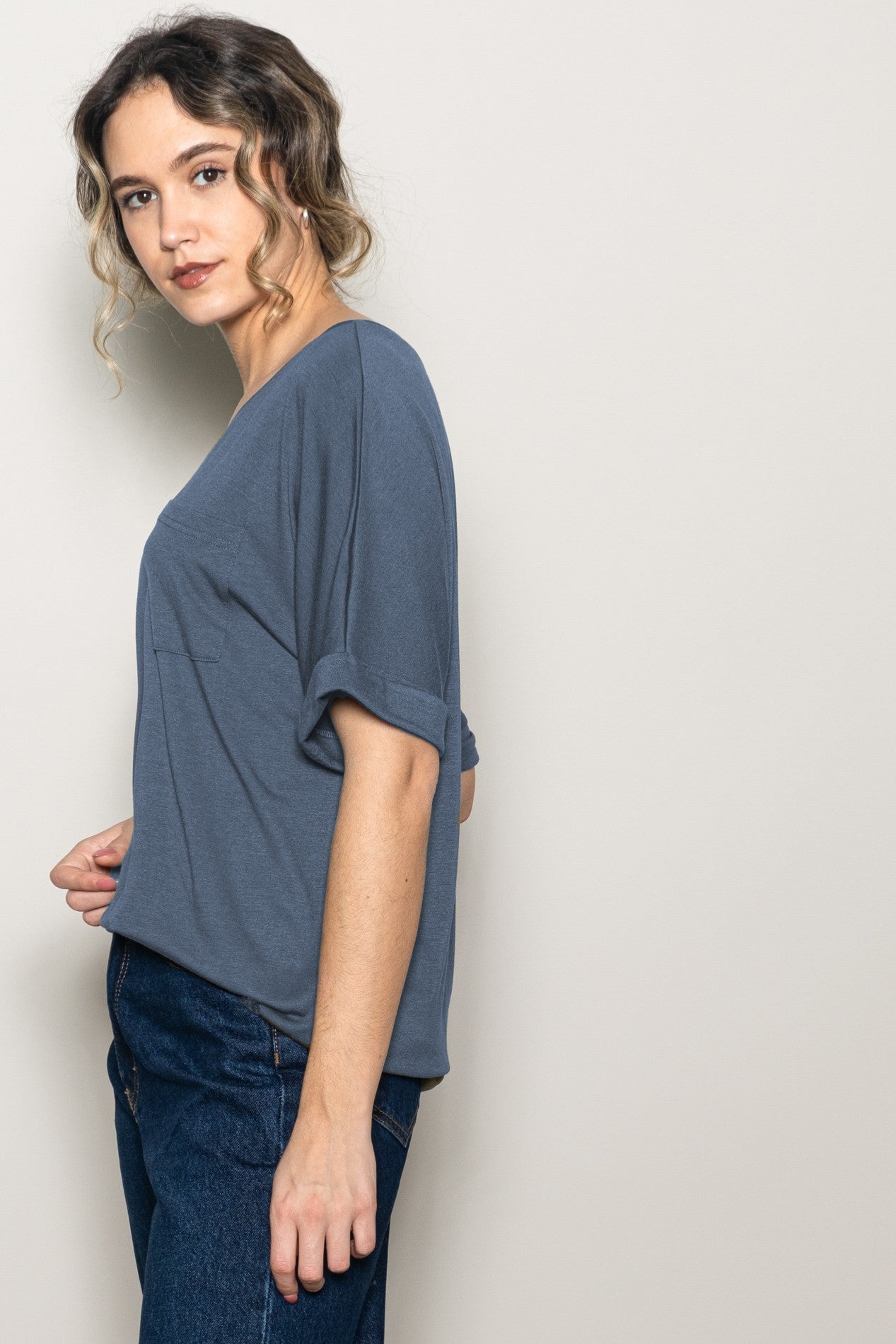woman wearing a loose-fitting gray casual t-shirt with rolled sleeves and blue jeans