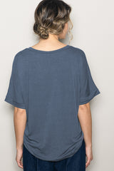 woman wearing a dark gray oversized t-shirt with short sleeves and a scoop neckline, viewed from the back