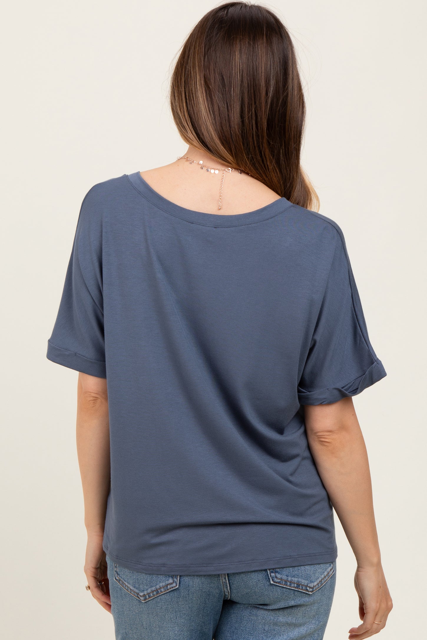 woman wearing a slate blue short sleeve maternity top with rolled sleeves, seen from the back