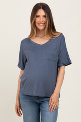 woman wearing a blue short sleeve v-neck maternity top with a front pocket and visible baby bump