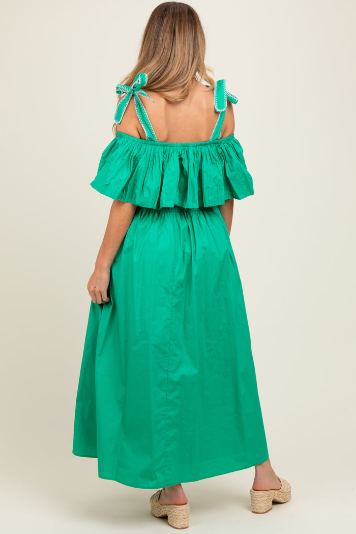 woman wearing a green off-the-shoulder maternity maxi dress with ruffled detailing and tie straps